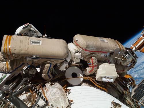 Two Russian Cosmonauts, both wearing spacesuits, work outside of the International Space Station during a spacewalk.