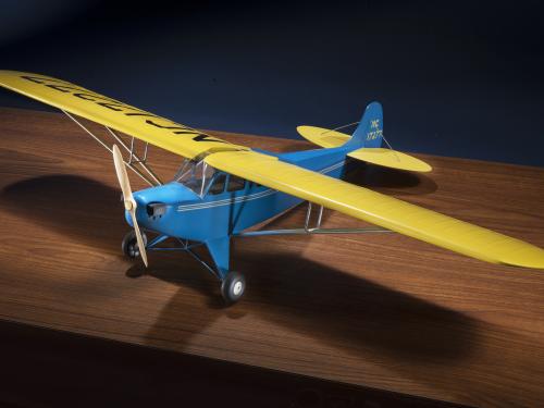 Diagonal front view of blue and yellow monoplane model with one engine represented by a wooden set of two blades.