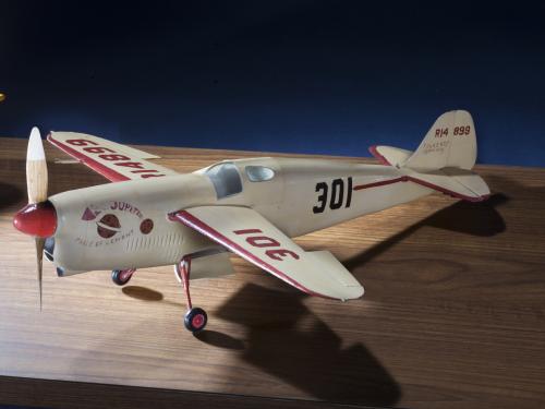 Side view of white monoplane model with one engine. The number 301 is painted in black on the rear of the fuselage and in red on the left wing.