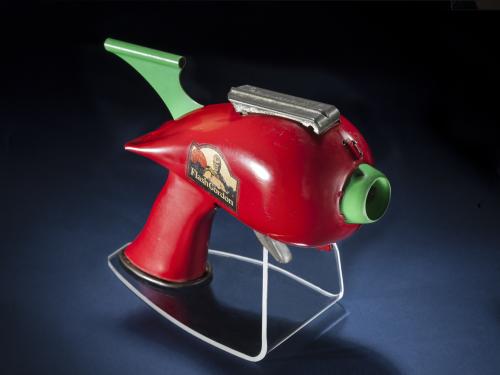 Side view of red-colored steel gun toy with light green trigger.