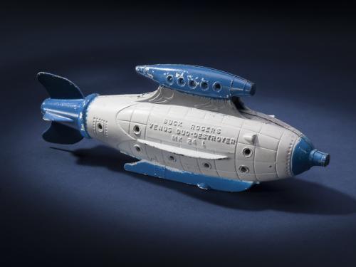 Side view of white torpedo-shaped destroyer toy with blue propellor, nose, and fins.