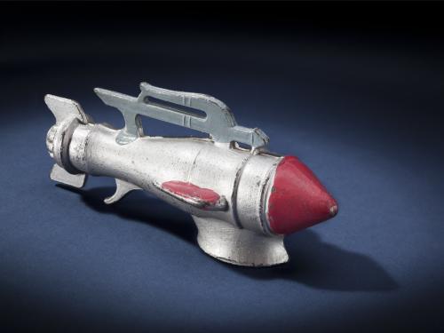 Side view of silver-colored metal missile-shaped spaceship with red nose.