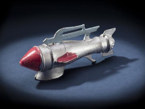 Side view of silver-colored metal missile-shaped spaceship with red nose.