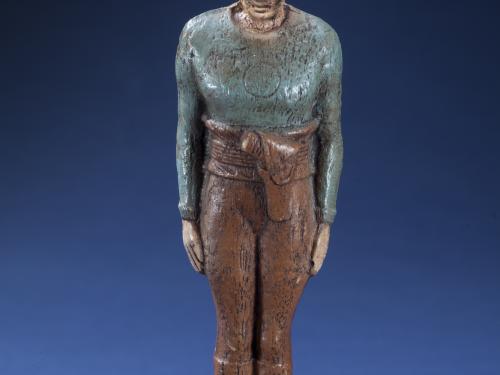 Front view of person-shaped statuette with blue-gray top and brown pants. "Flash Gordon" is painted in black on the front of the base.