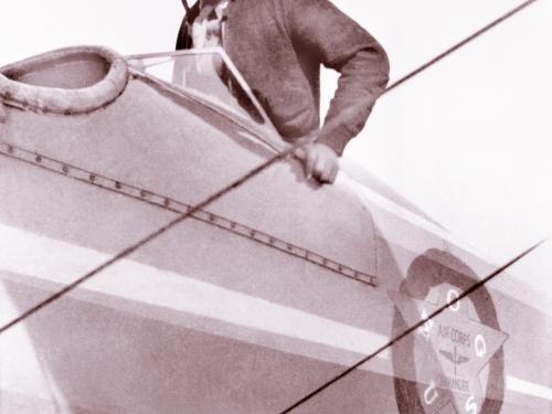 Earl W. Renfroe, an African-American male pilot, stands in the cockpit of a biplane.