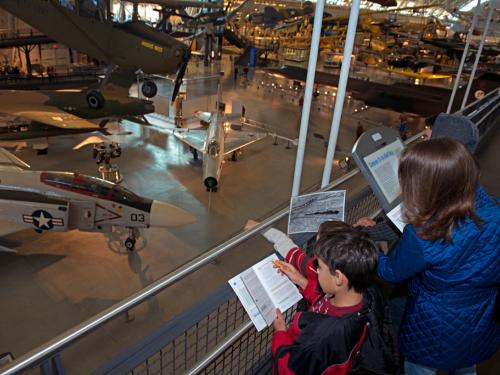 Three younger Museum guests observe objects in the Museum while playing a Museum-sanctioned alternate reality game.