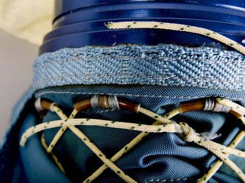 Close-up view of developmental blue glove. Thin, tan rope acts as a lacing system under a blue skirt.