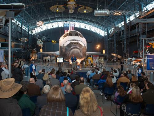 Museum visitors listen to a presentation in the Space Hangar of the Steven F. Udvar-Hazy Center during an open house event.