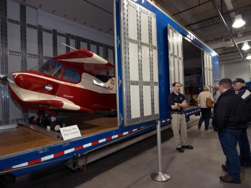 A Museum staff member provides visitors a lesson on artifact transport in front of a partially open storage unit.