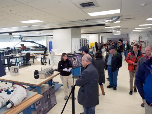 A member of the Museum's conservation staff presents work they have done to conserve objects to many visitors inside the Museum's conservation laboratory.