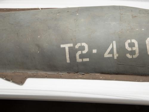 A gray-colored engine cover belonging to a gray military aircraft. The engine cover features the marking "T2-490" on the right side of the visible cover.