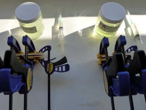 A pair of tool sets used to perform resin consolidation experiments. The tools include a syringe, a jar of a yellow transparent object, and a large blue, black, and yellow object.