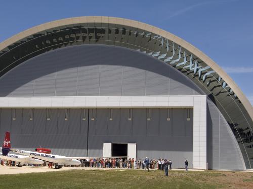 A white and red aircraft stands in front of a set of doors in the collections storage area of the Udvar-Hazy Center.