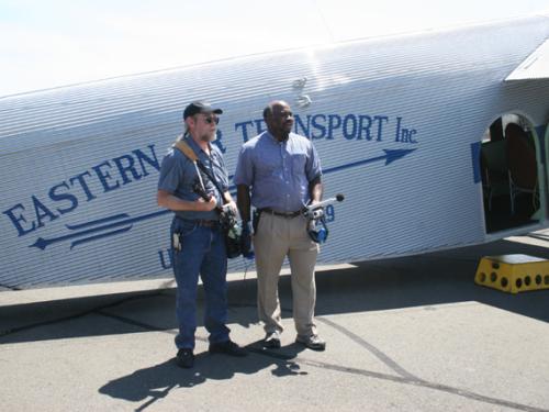 Two Smithsonian employees stand in front of white Ford Tri-Motor aircraft.