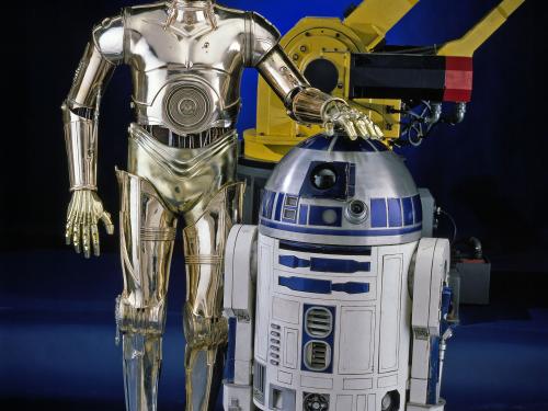 R2-D2, a blue and white robot "droid" from the Star Wars franchise, and C-3PO, a golden-metalic robot "droid" from the Star Wars franchise, stand next to each other on display at the museum.