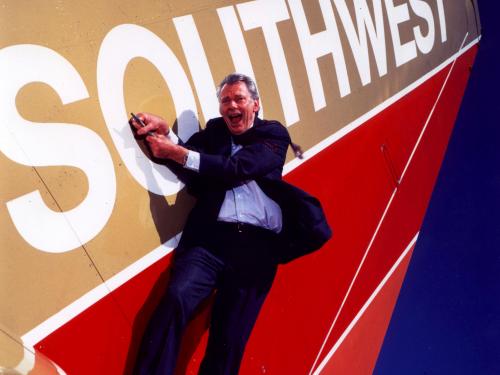 Herb Kelleher, a white man, lies next to an aircraft wing with Southwest livery