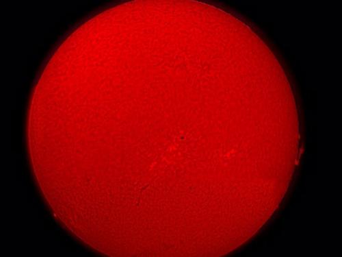 A semi-sphere view of the Sun with sunspots and granulation surface details.