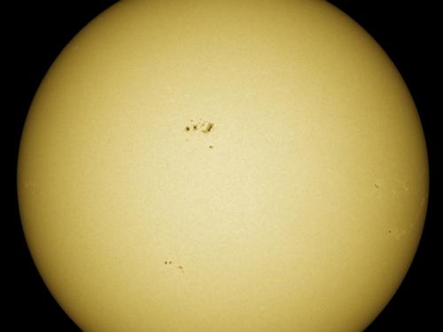 Disk view of the Sun with visible sunspot groups near the center of the Sun's visible surface.