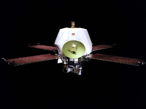 A spacecraft with an oblong-shaped base with one satellite and four solar panels attached to the sides of the base.