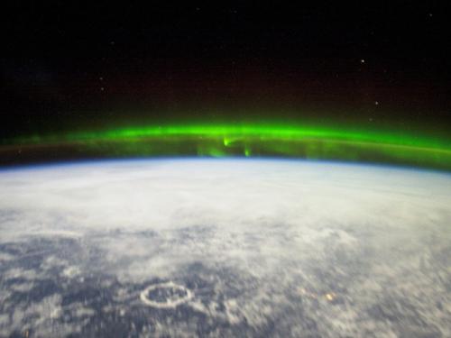 A green reflection of the Aurora Borealis seen from the International Space Station above Earth.