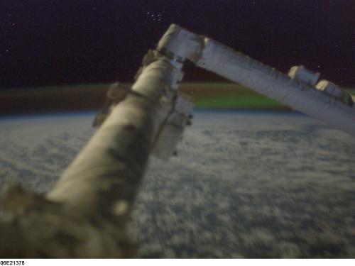 A large, arm-like object on the International Space Station in front of the Aurora Borealis in the background.