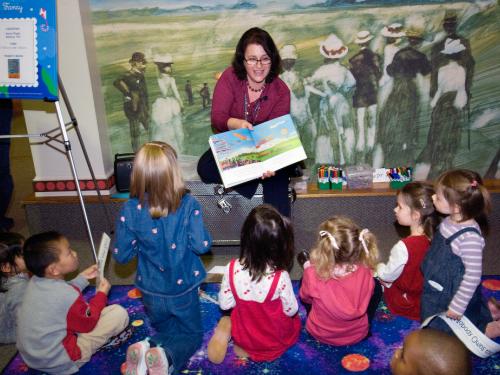 An educator reads a book to young people. 