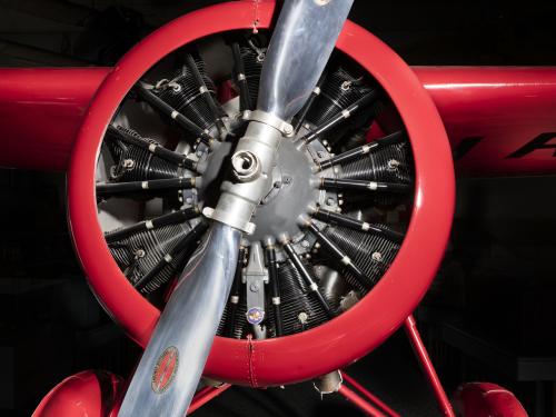 Front engine and silver single-blade propeller on red Amelia Earhart Lockheed Vega 5B aircraft