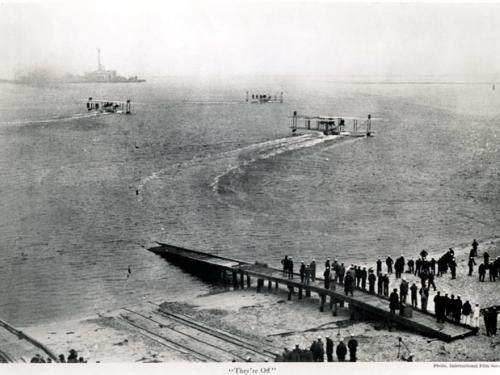 Three aircraft on the water with people on the dock