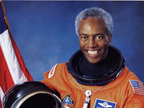 Guion Bluford, an African-American male astronaut, poses formally in an astronaut suit with his helmet.