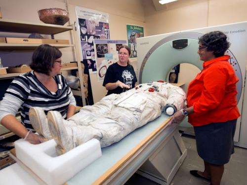 Three Smithsonian staff members prepare Neil Armstrong's spacesuit for a CT scan.