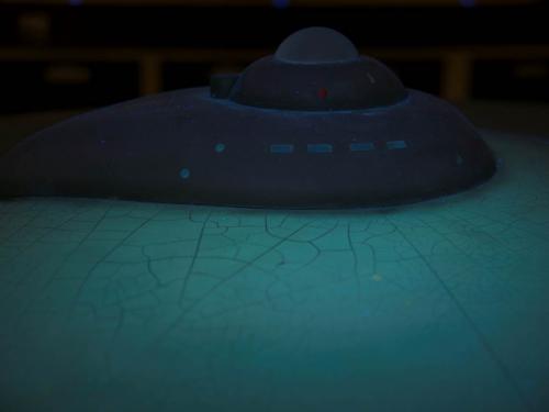 A partial view of the top portion of the Enterprise Studio Model under special lighting. Cracks can be seen on the saucer of the spacecraft from age.