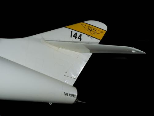 Tail of white Douglas D-558-2 aircraft with yellow stripe with "NACA" insignia and "144" written in black letters