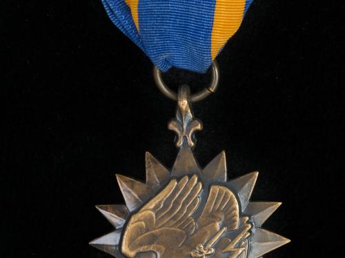 Bronze sunburst medal with eagle holding lightning bolts on blue silk ribbon with gold stripes