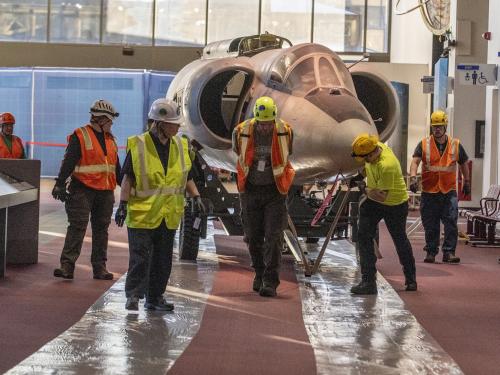 The forward fuselage of the Lockheed U-2 aircraft is moved by staff and contractors.