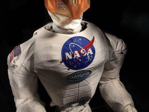 Frontal view of a body of a robot with arms, chest with a NASA logo, and an orange face cover.