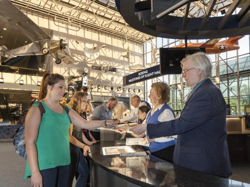 Visitors being helped by the Welcome Center in the Boeing Milestones of Flight Hall