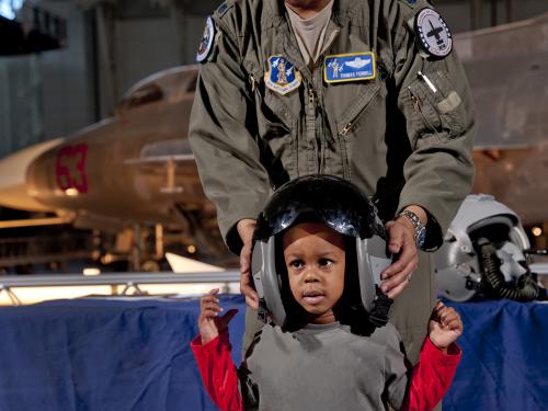 An African-American child has an African-American male member of the Pennsylvania Air Force National Guard place a helmet on his head.