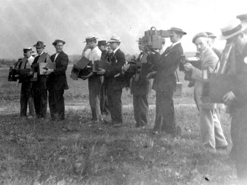 Black and white photo of photographers standing in a row. 