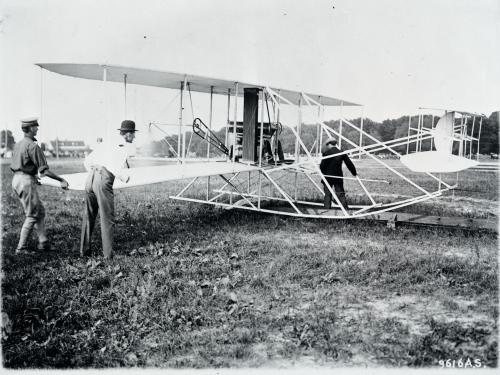 Black and white photograph of Wilbur Wright preparing his aircraft.