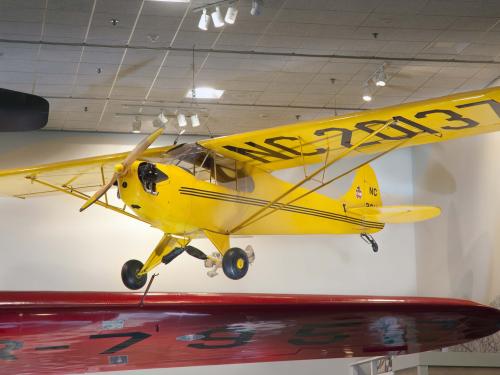 Yellow monoplane with one engine displayed as hanging in the Museum.