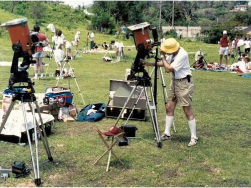 Man peers into a telescope at a large field. 