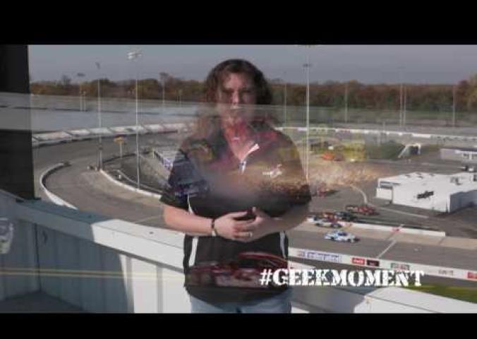 A video outside of a race track with a person speaking about race cars.