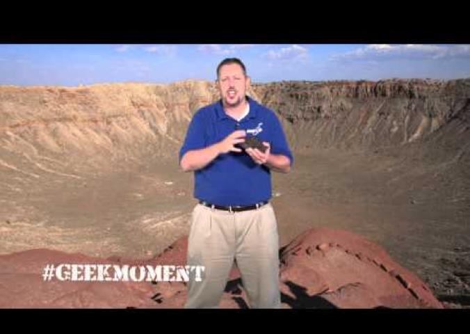 A man speaks about meteors inside a meteor crater.