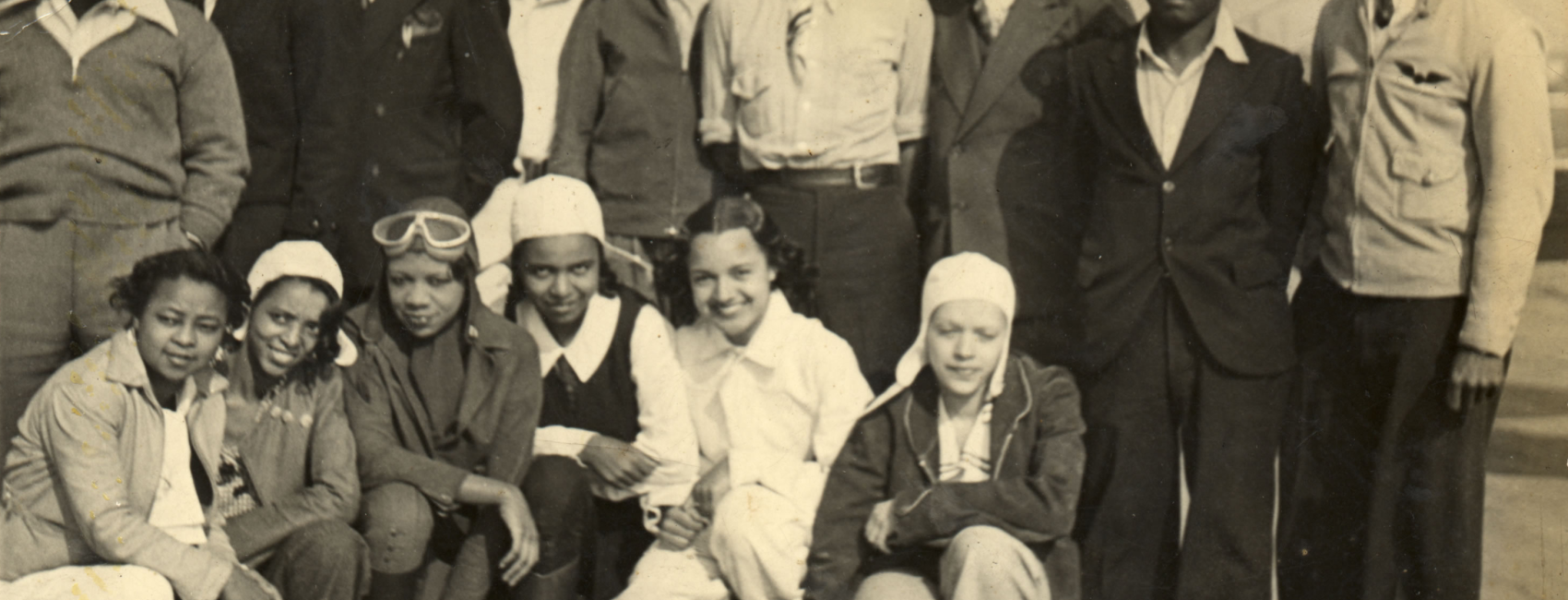 Several people, men and women, some in flying gear, smile at the camera.