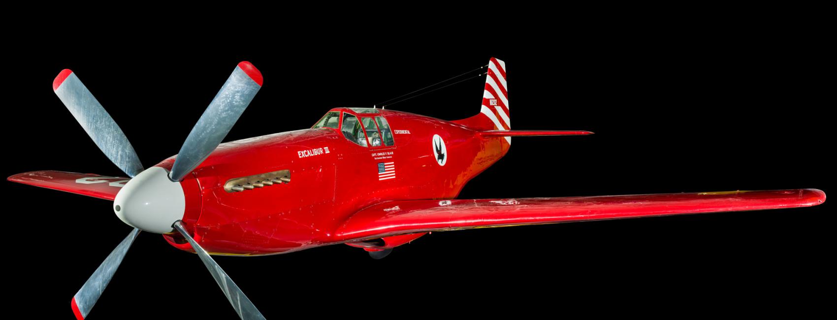 View of a red and white plane. Painted below the cockpit is the American flag.