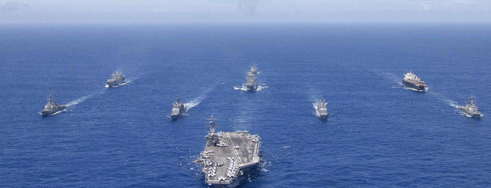 Aerial view of the aircraft carrier USS Ronald Reagan and support ships at sea.