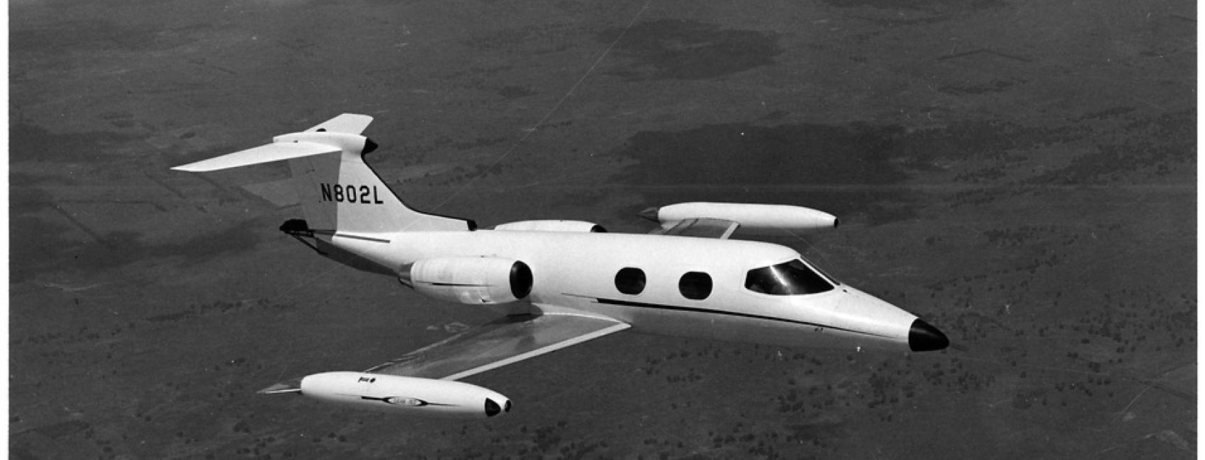 A side view of a small and sleek looking aircraft in flight, as if taken from the window of a nearby aircraft.