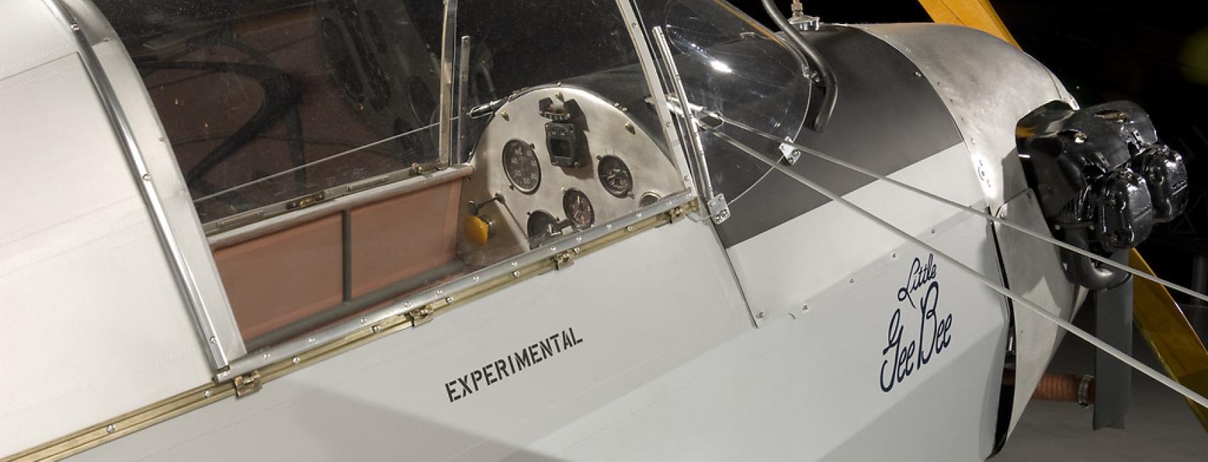 A side view of front half of a gray colored prop plane. Written under the cockpit window is "experimental."