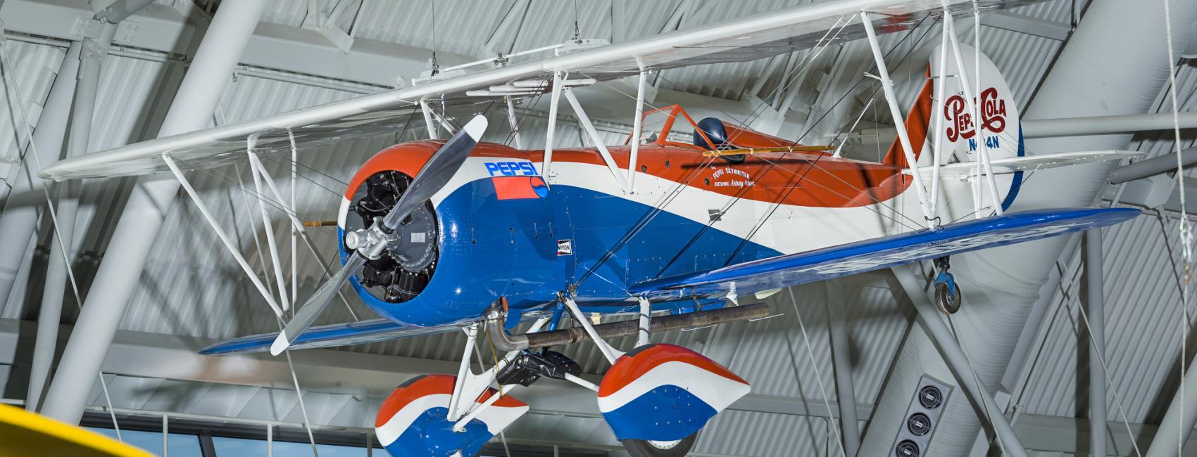 Red white and blue biplane with Pepsi-Cola logo on the back