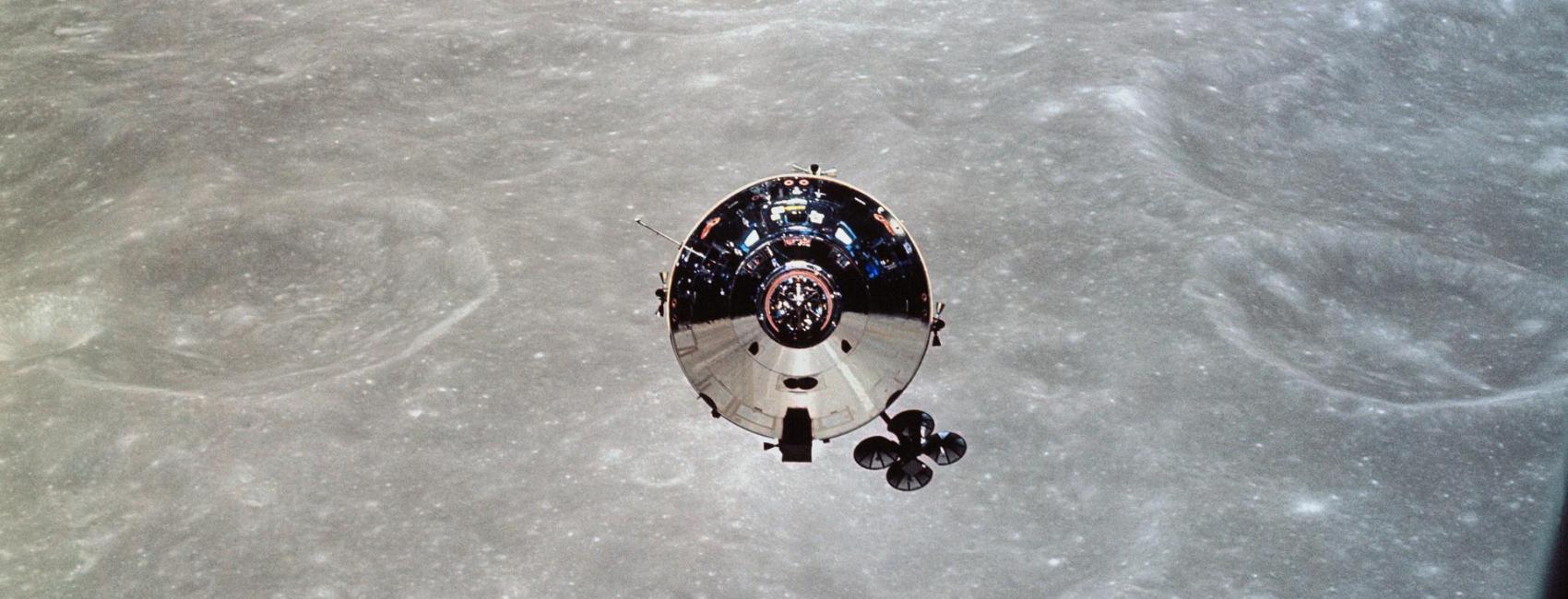 A silver cylindrical module with a cone-shaped lid floats above the Moon.